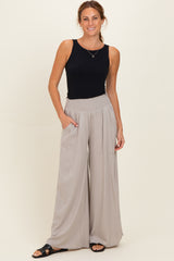 woman wearing a black sleeveless top with high-waisted light gray wide-leg pants featuring pockets