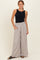 woman wearing a black sleeveless top with high-waisted light gray wide-leg pants featuring pockets