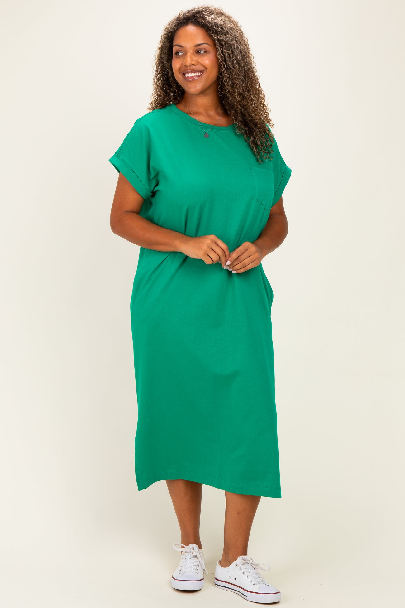 woman wearing a green plus-size midi dress with short sleeves and a pocket detail