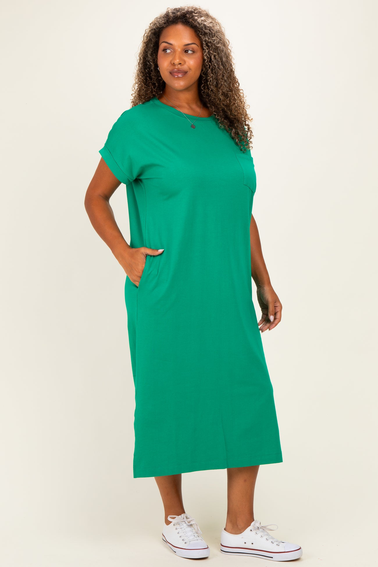 woman wearing a green short sleeve plus size maxi dress with side pockets and white sneakers