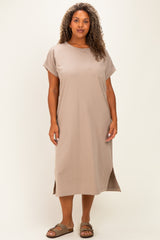 woman wearing a taupe short sleeve midi dress with a pocket and side slits, standing on a plain background
