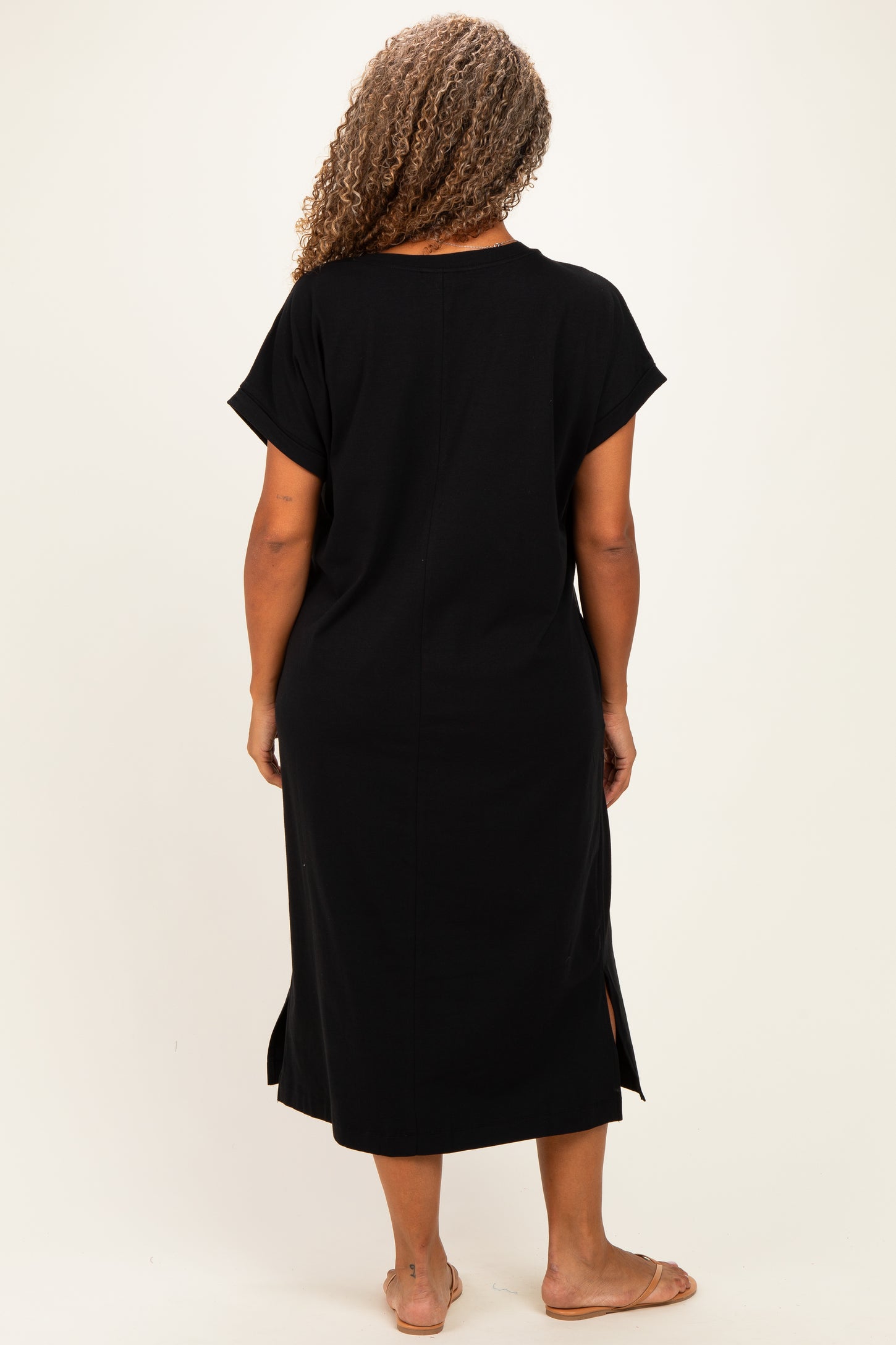 woman wearing a black midi dress with short sleeves and side slits, shown from the back
