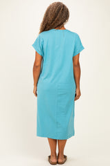 woman wearing a turquoise short sleeve plus size midi dress with a straight cut and a back slit