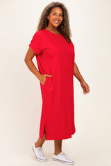 woman wearing a red plus size t-shirt dress with short sleeves and side pockets, standing with a smile