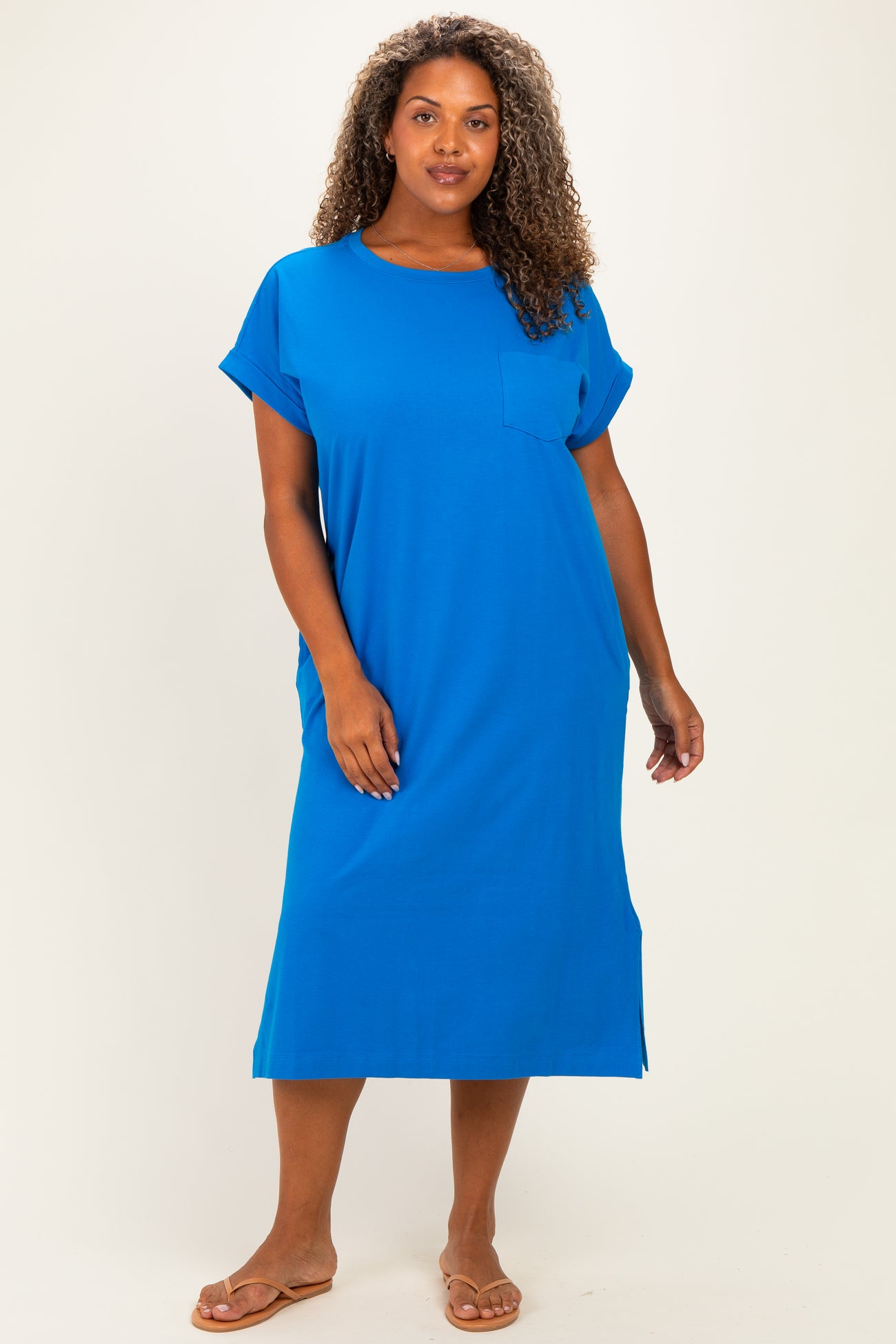 woman wearing a bright blue plus-size casual dress with short sleeves and a front pocket, standing confidently