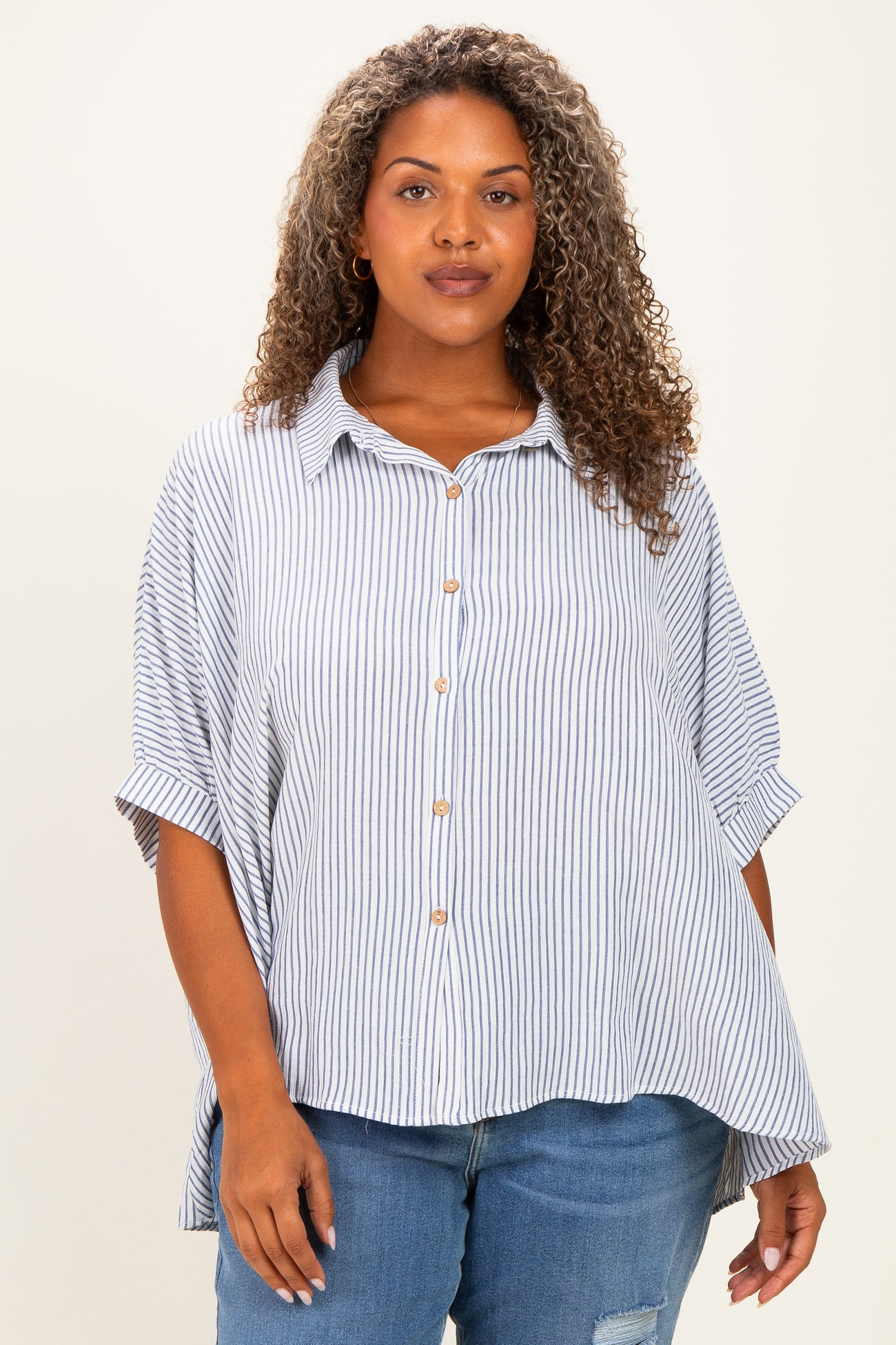 woman wearing a striped button-up shirt with short sleeves and a relaxed fit paired with distressed jeans