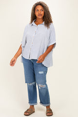 woman wearing a striped button-up poncho top with oversized sleeves and distressed denim jeans