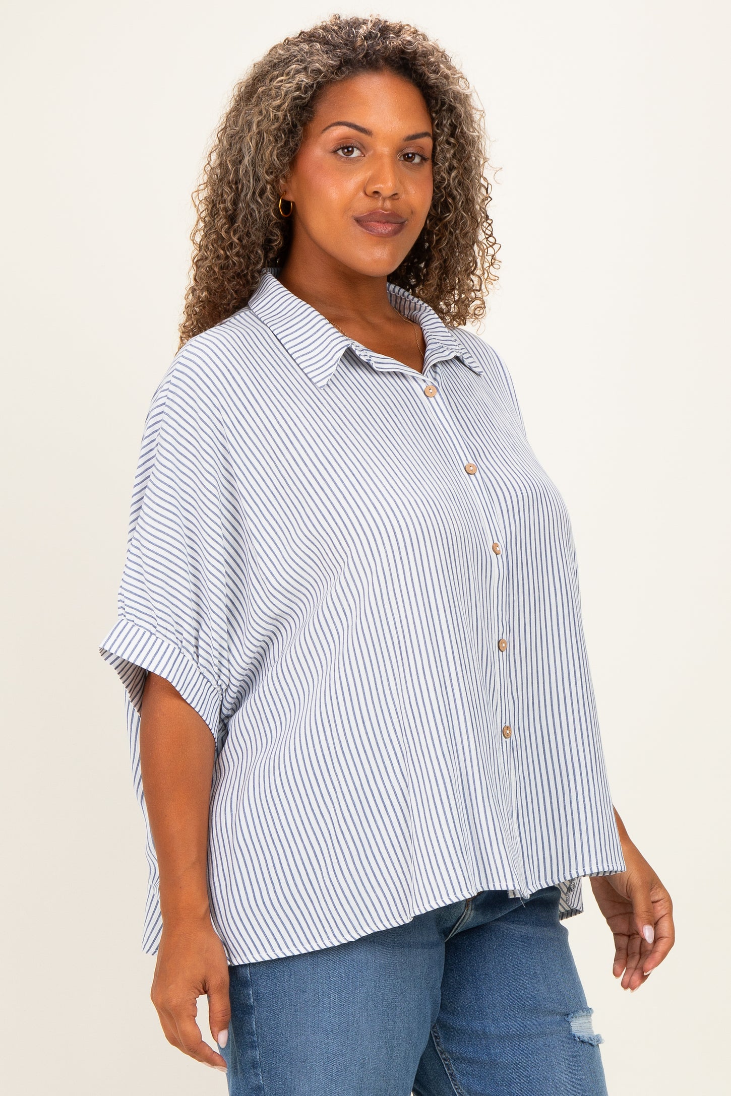 woman wearing a blue and white striped short sleeve button-up shirt paired with distressed denim jeans