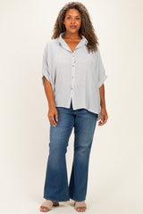woman wearing a striped oversized button-up shirt with short sleeves and flared jeans