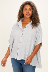 woman wearing a striped button-up blouse with a relaxed fit and rolled sleeves, paired with blue jeans