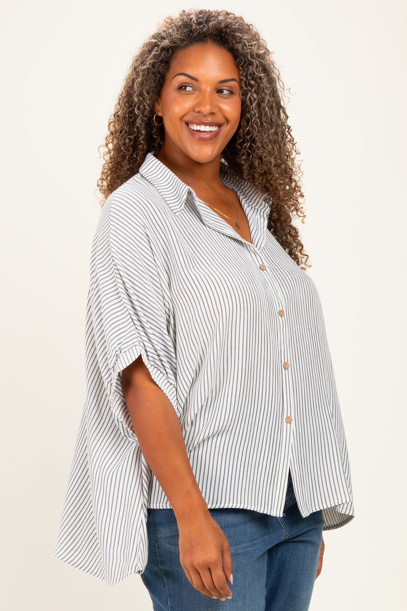 woman wearing a striped button-up plus size shirt with a relaxed fit and rolled sleeves
