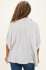 woman wearing a loose-fitting striped plus-size top with wide sleeves and a back pleat detail.