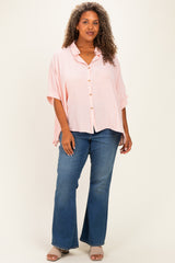 woman wearing a light pink and white striped oversized button-up shirt with rolled sleeves and blue flared jeans
