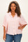 woman wearing a pink and white striped oversized button-up shirt with short sleeves and blue jeans