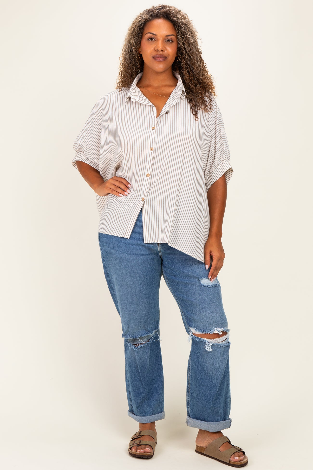 woman wearing a striped oversized button-up shirt with rolled sleeves and distressed blue jeans