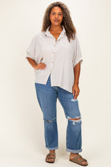 woman wearing a striped oversized button-up shirt with rolled sleeves and distressed blue jeans