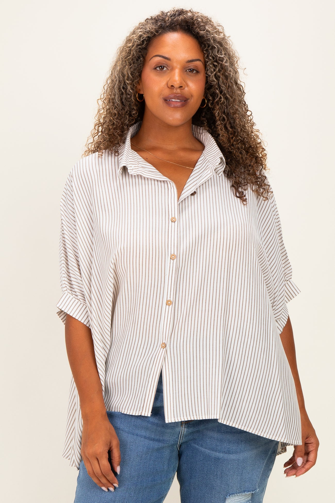 woman wearing a beige and white striped plus size button-up shirt with rolled sleeves and an asymmetrical hem