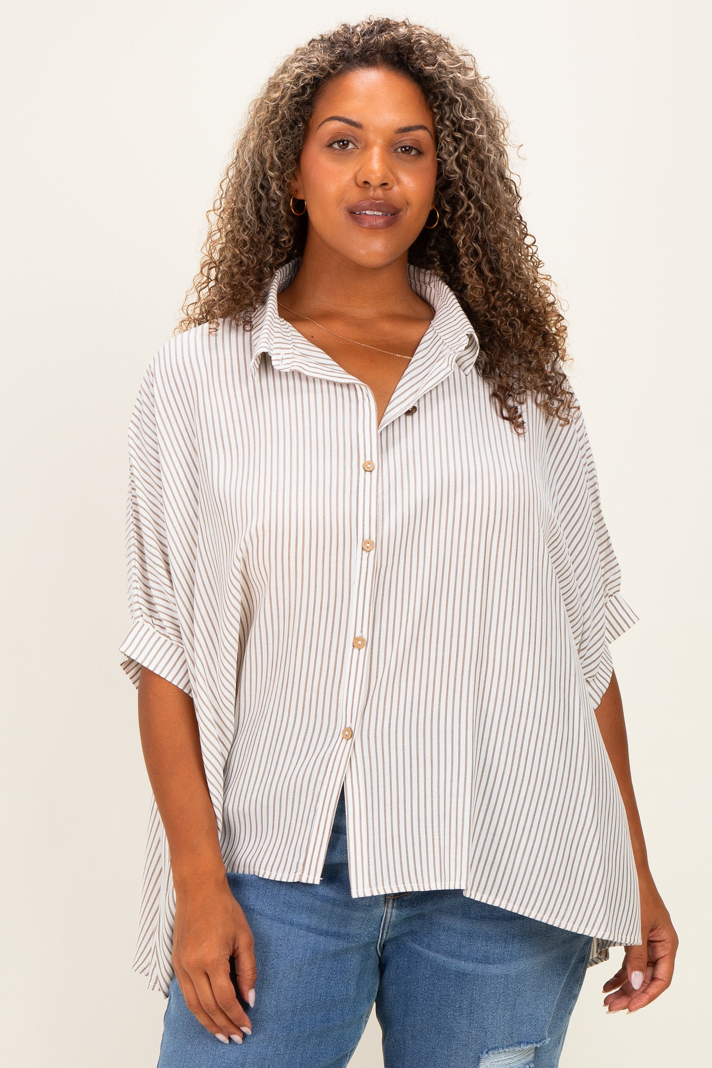 woman wearing a beige and white striped plus size button-up shirt with rolled sleeves and an asymmetrical hem