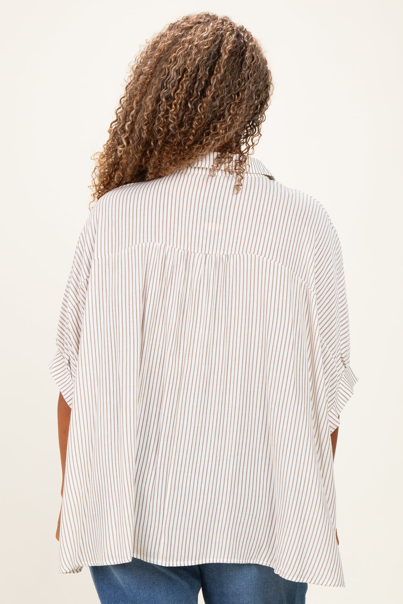 woman wearing a striped plus size blouse with a relaxed fit and short sleeves, shown from the back