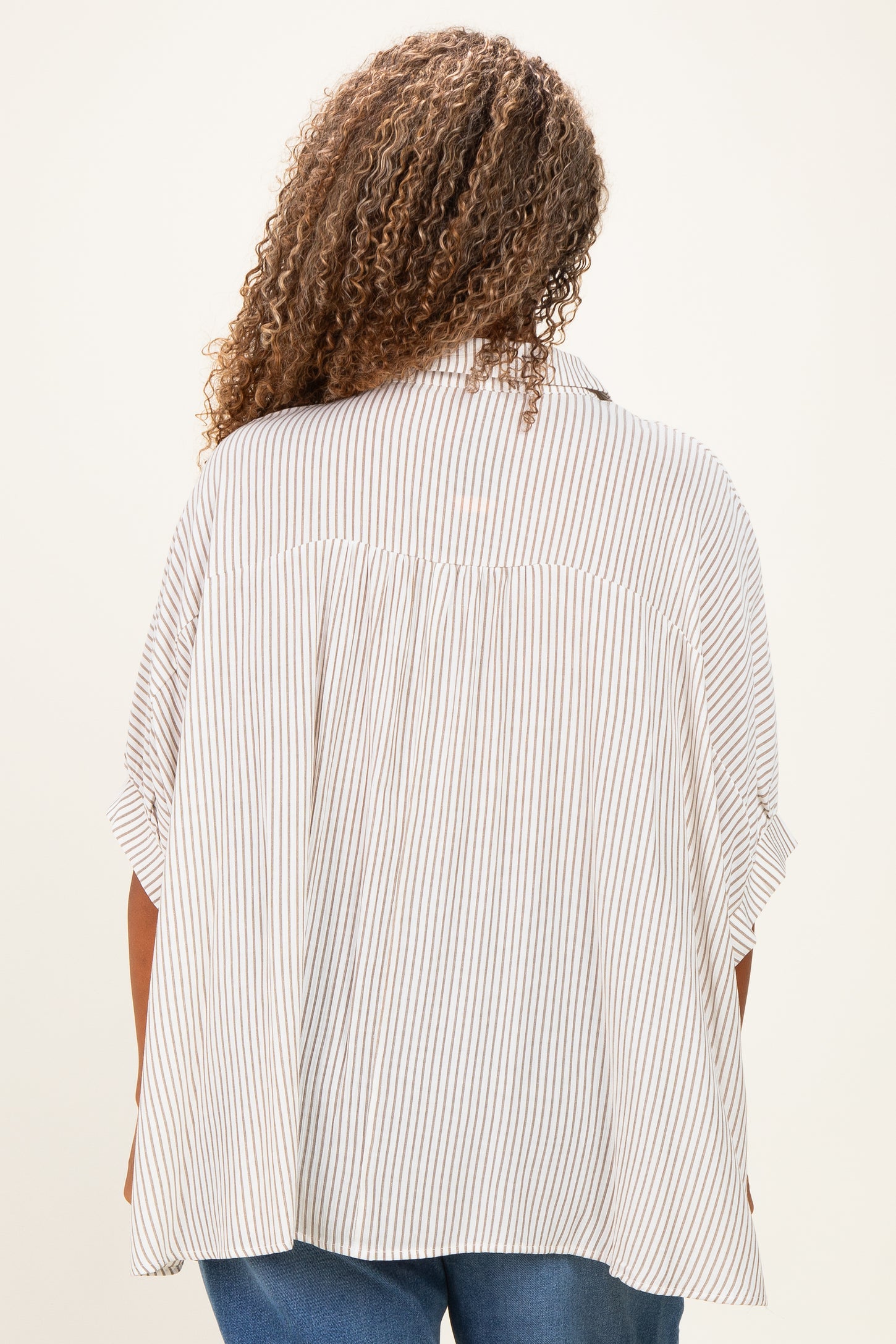 woman wearing a striped plus size blouse with a relaxed fit and short sleeves, shown from the back