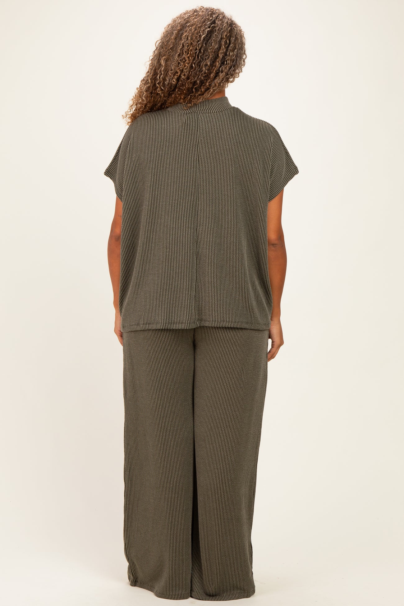 woman wearing a dark olive green short sleeve plus size top and matching wide leg pants, viewed from the back
