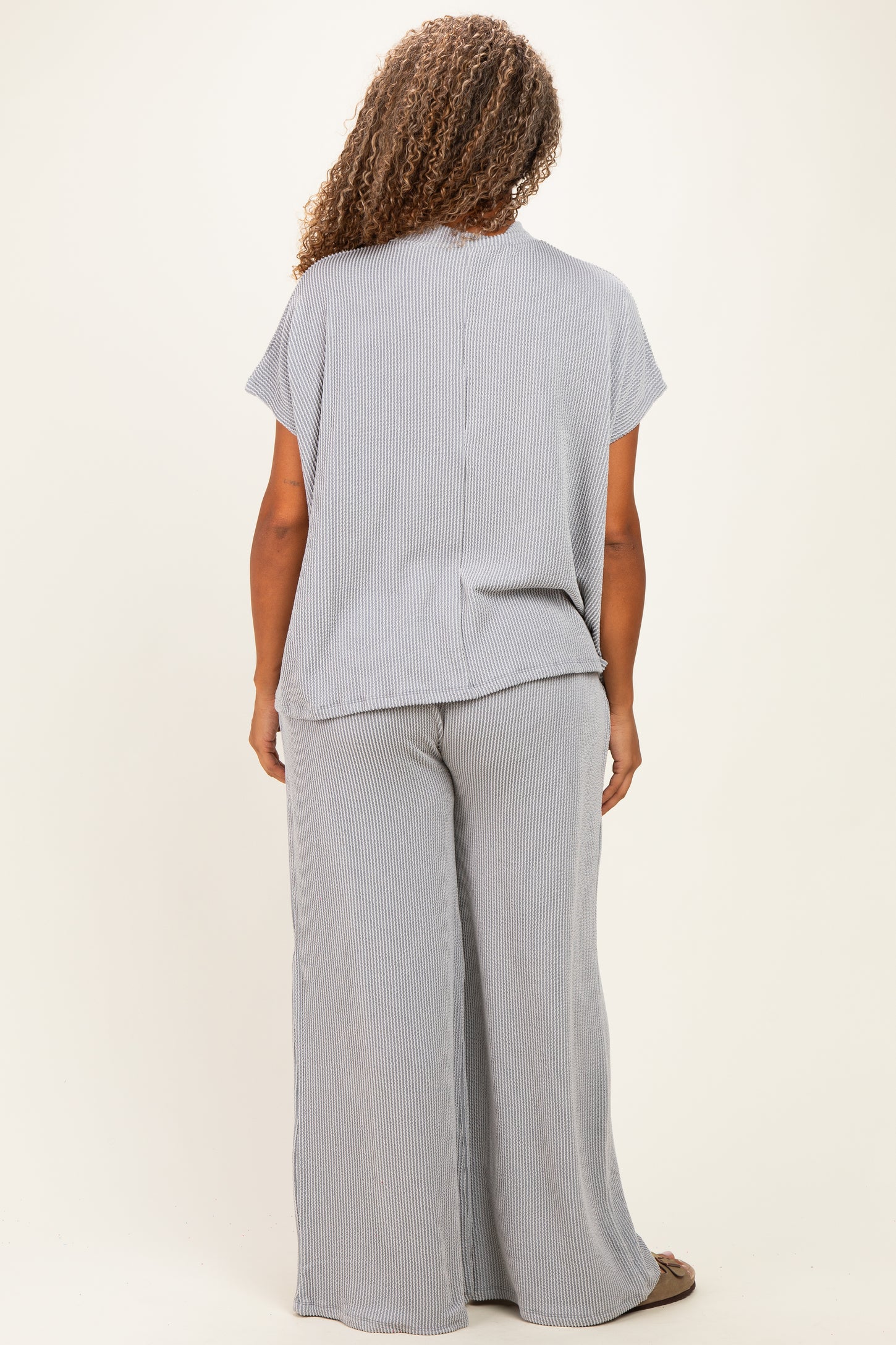 woman wearing a light gray and white striped plus size lounge set with wide leg pants and short sleeves, seen from the back