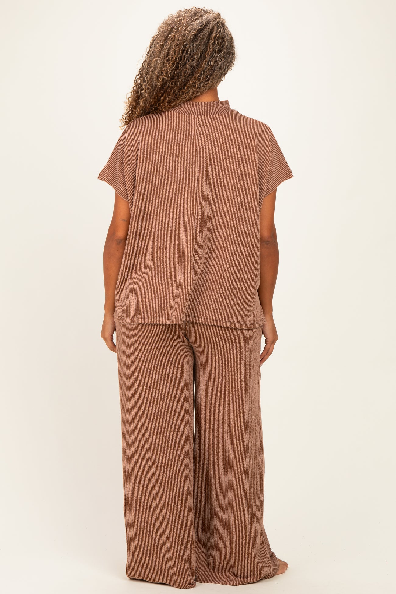 woman wearing a brown striped plus size loungewear set with a loose fit top and wide leg pants, viewed from the back