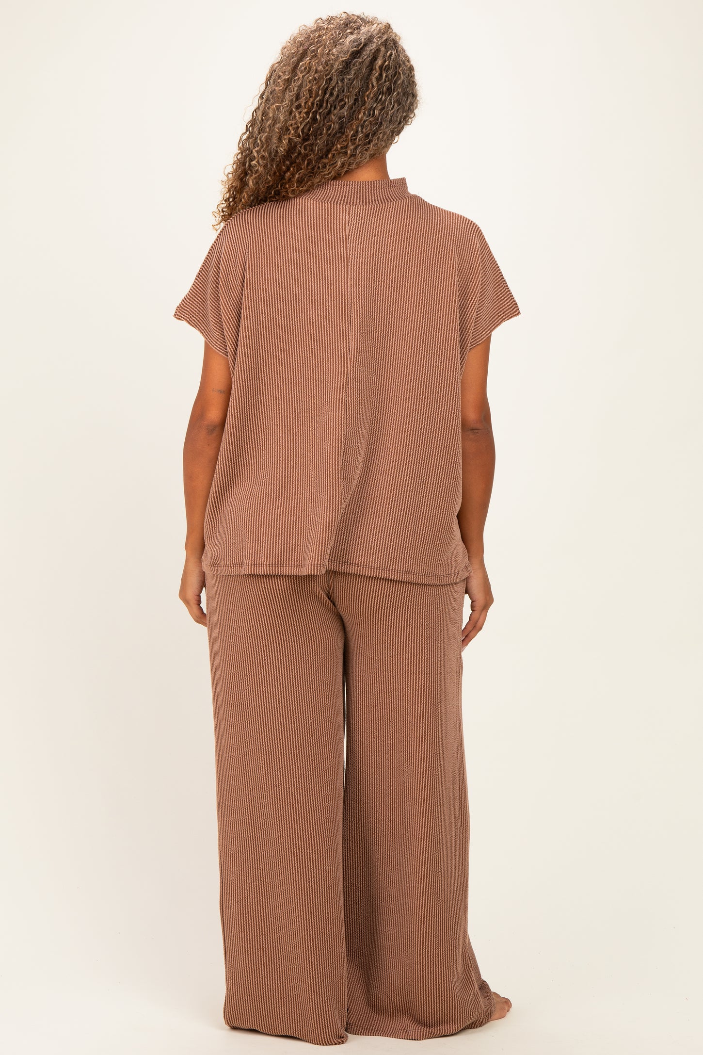 woman wearing a brown striped plus size loungewear set with a loose fit top and wide leg pants, viewed from the back