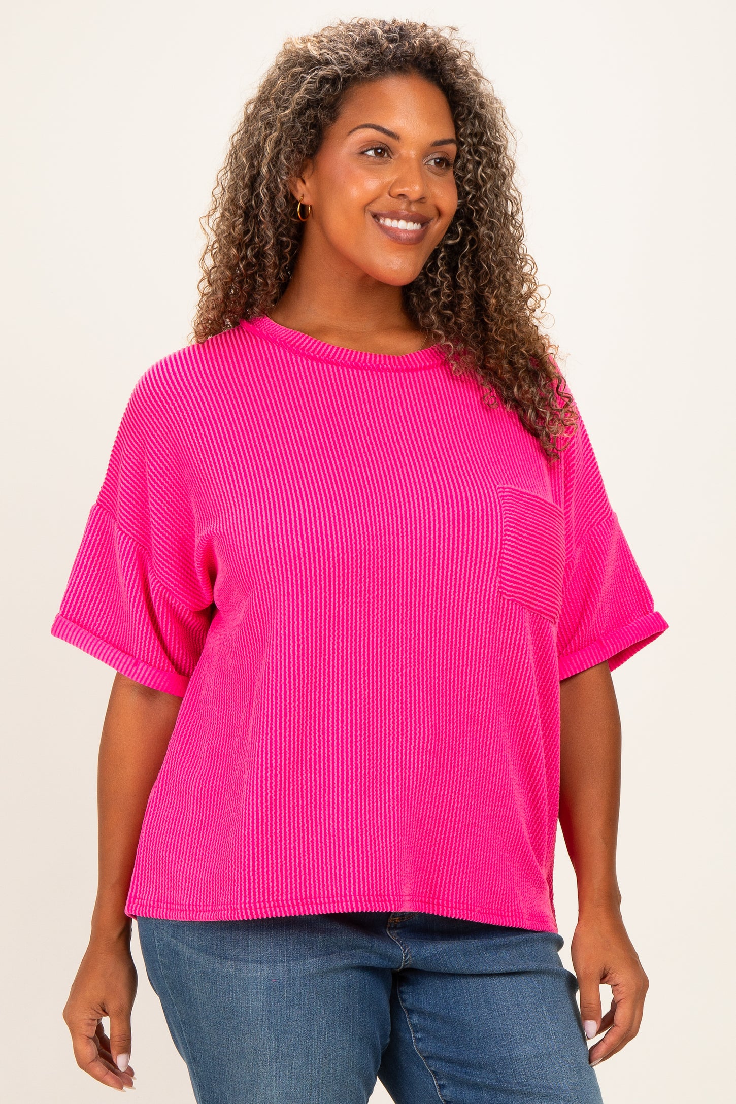 woman wearing a bright pink plus size ribbed t-shirt with short sleeves and a front pocket