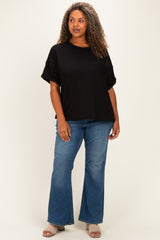 woman wearing a black oversized ribbed top with a pocket and flared blue jeans