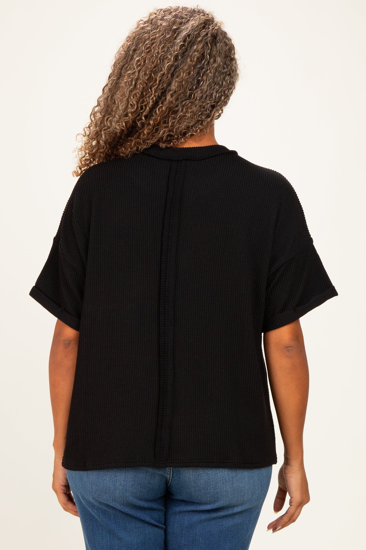 woman wearing a black textured plus size top with short sleeves, viewed from the back