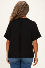 woman wearing a black textured plus size top with short sleeves, viewed from the back