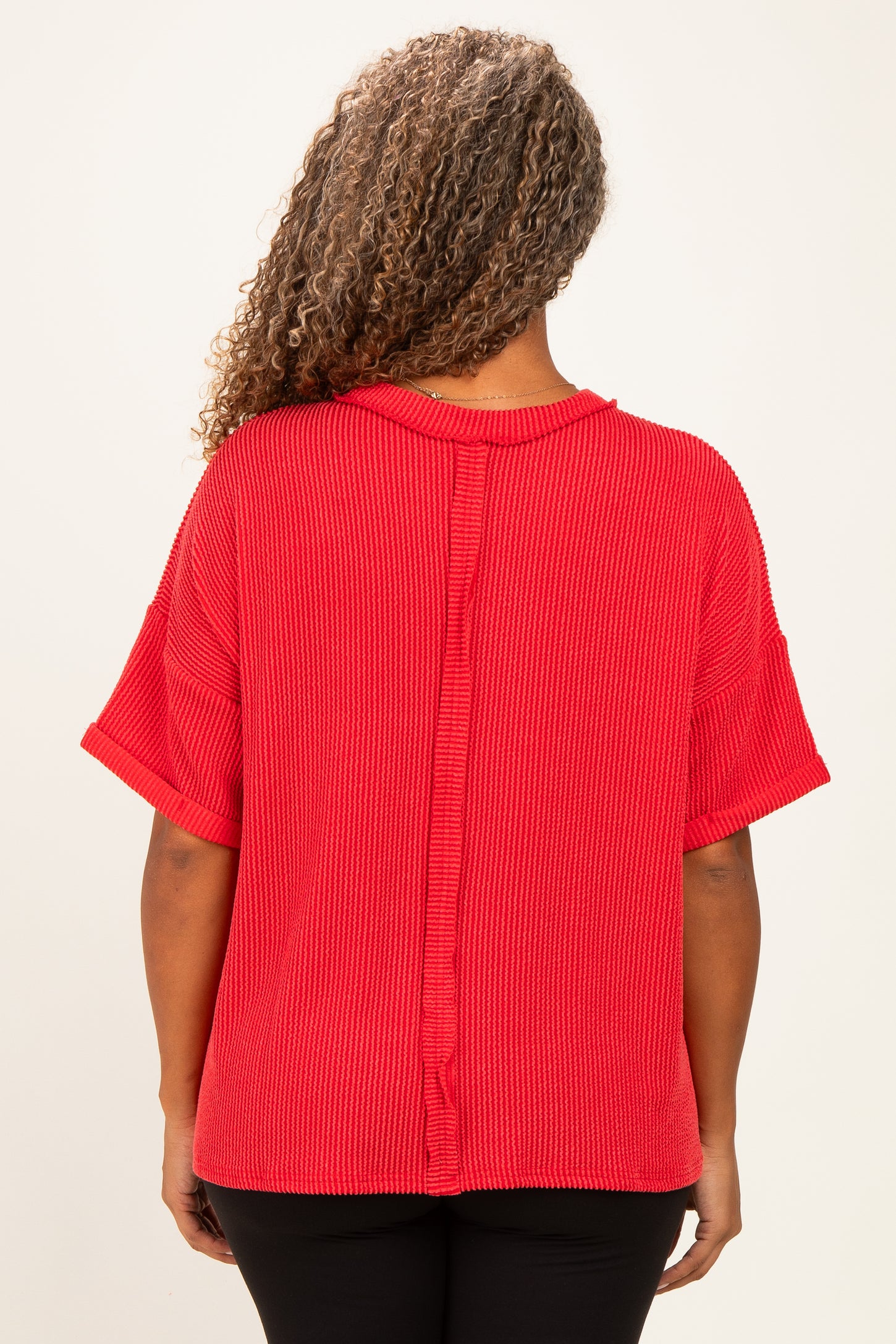 woman wearing a red oversized short sleeve sweater with a textured finish and back seam detail