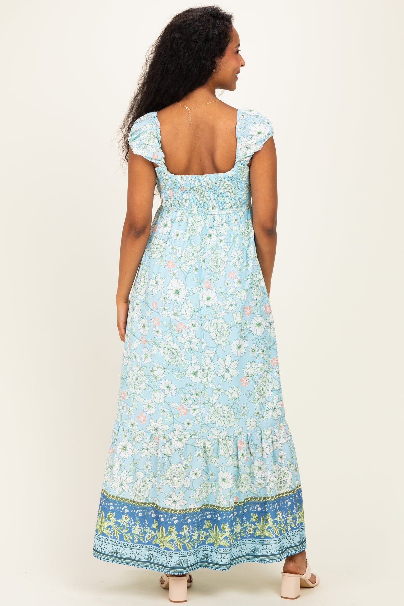 woman wearing a blue floral print maternity maxi dress with puff sleeves and a smocked back