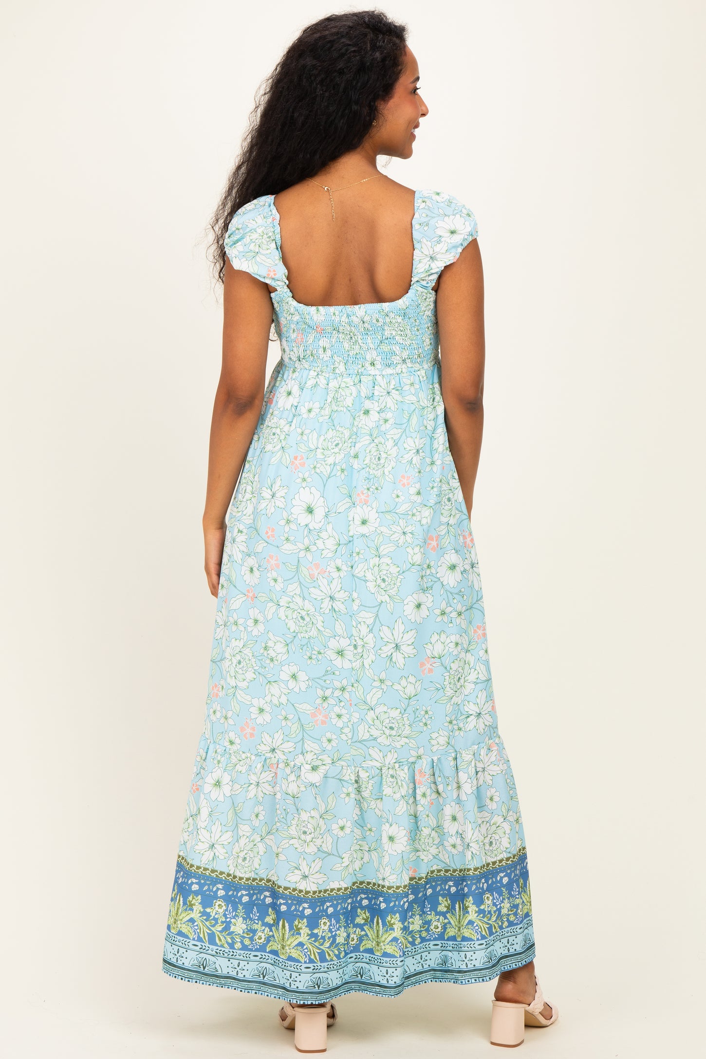woman wearing a blue floral print maternity maxi dress with puff sleeves and a smocked back