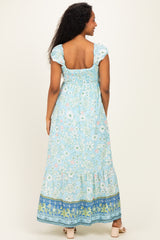 woman wearing a blue floral print maternity maxi dress with puff sleeves and a smocked back