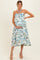 woman wearing a floral strapless maternity dress, showing her baby bump while posing against a light background