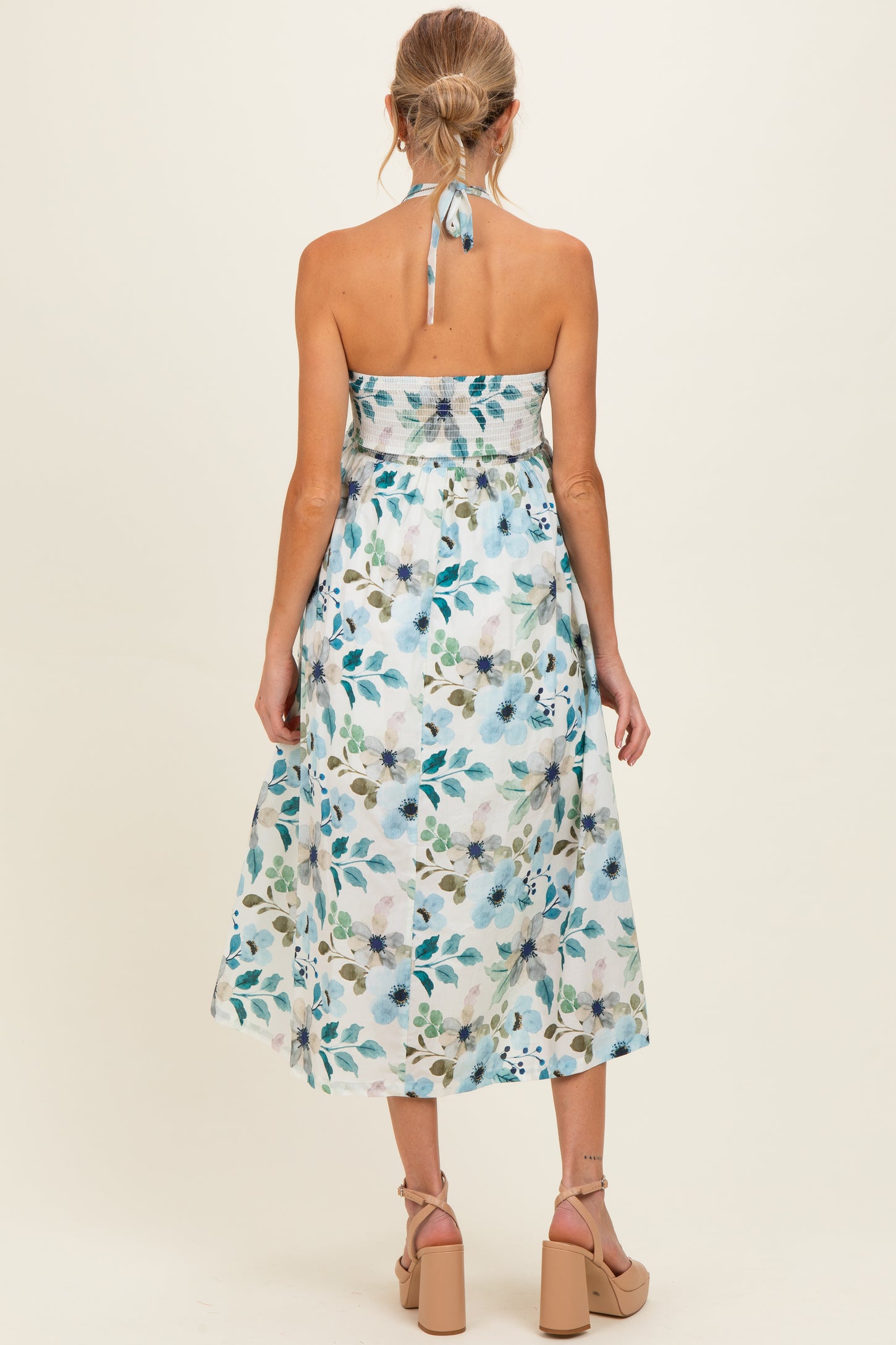maternity wear floral print halter neck midi dress with a fitted bodice and a flowing skirt, model seen from the back