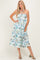 woman wearing a floral halter neck maxi dress in shades of blue and green, styled with green heeled sandals