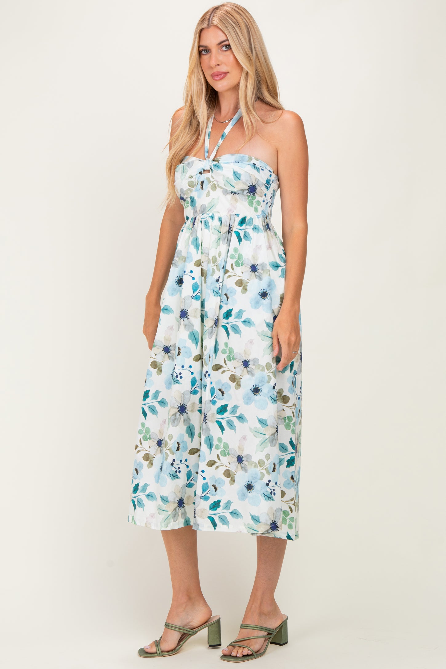 woman wearing a strapless floral midi dress with a tie neckline and cinched waist, styled with green heeled sandals