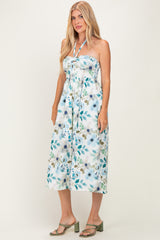 woman wearing a strapless floral midi dress with a tie neckline and cinched waist, styled with green heeled sandals