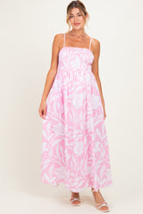 woman wearing a pink floral maternity maxi dress with spaghetti straps and a smocked bodice, showcasing a baby bump
