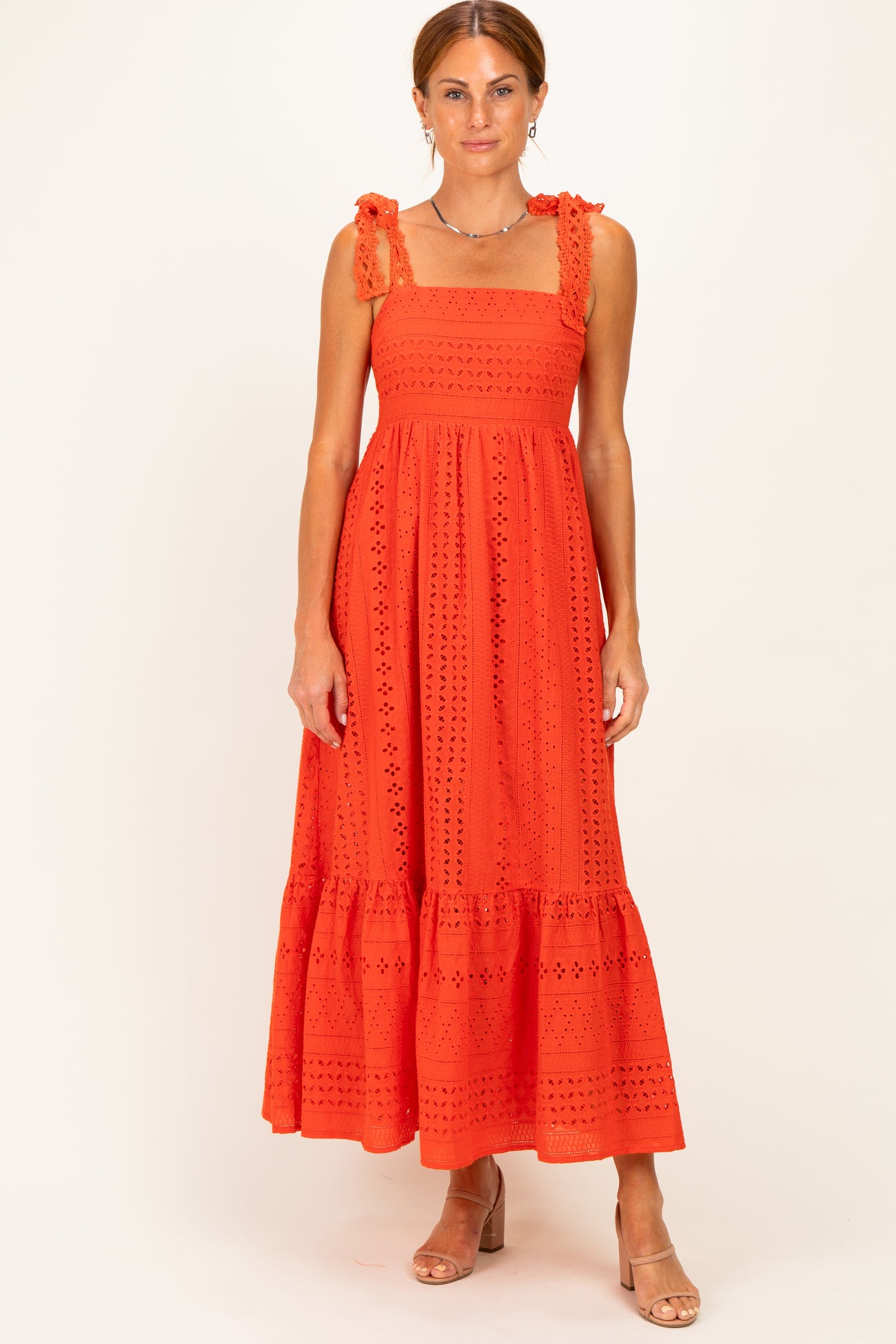 woman wearing an orange maxi dress with square neckline and ruffled straps, featuring eyelet details and a tiered hem