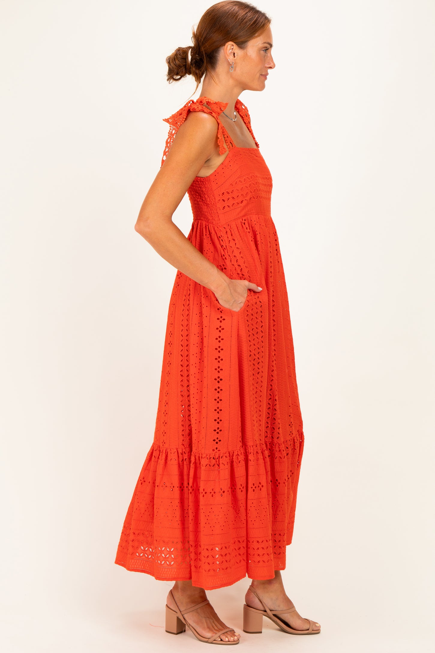 woman wearing a red sleeveless maxi dress with eyelet details and ruffled straps, standing in profile