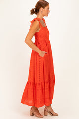 woman wearing a red sleeveless maxi dress with eyelet details and ruffled straps, standing in profile