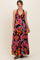 woman wearing a black maternity maxi dress with vibrant floral patterns and a halter neckline, showcasing her baby bump