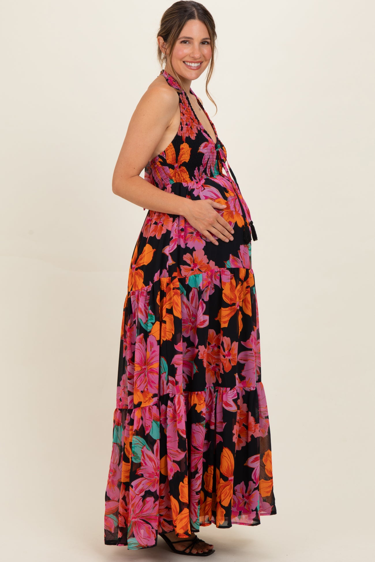 woman wearing a black halter neck floral maternity maxi dress with a visible baby bump