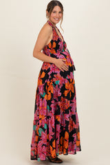 woman wearing a black halter neck floral maternity maxi dress with a visible baby bump