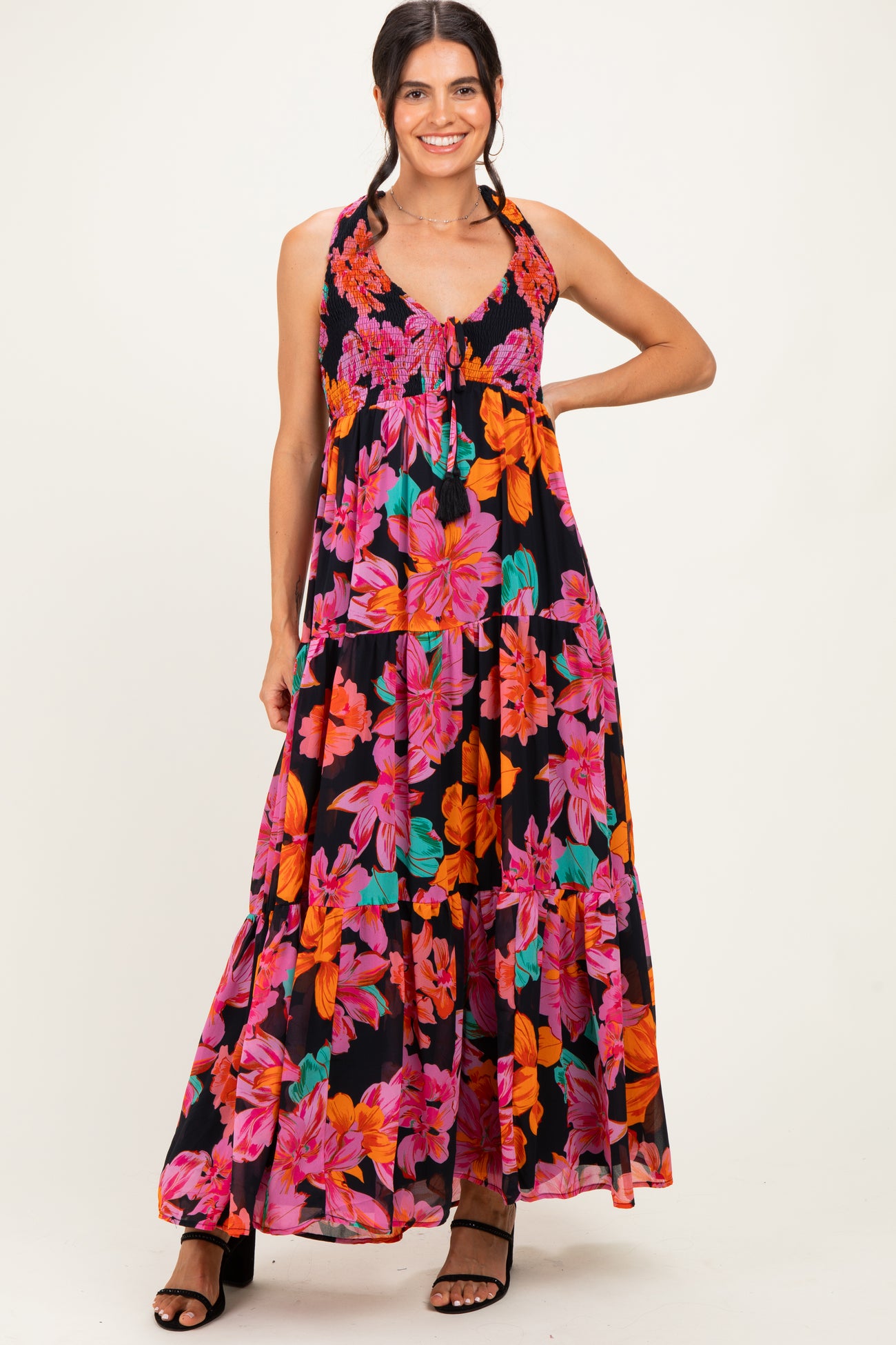 woman wearing a black maxi dress with vibrant pink and orange floral prints and a smocked bodice