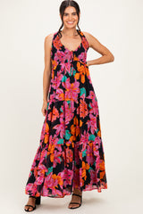 woman wearing a black maxi dress with vibrant pink and orange floral prints and a smocked bodice